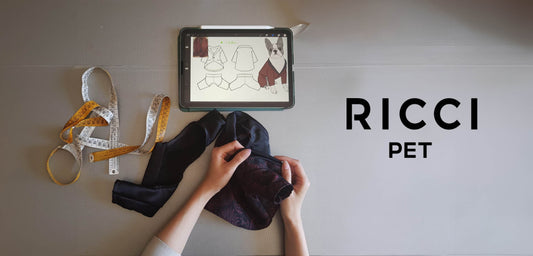two hands working a tailoring fabric for dogs and cats. in the photo there is a tape measure and an iPad with the drawing of elegant clothes for dogs