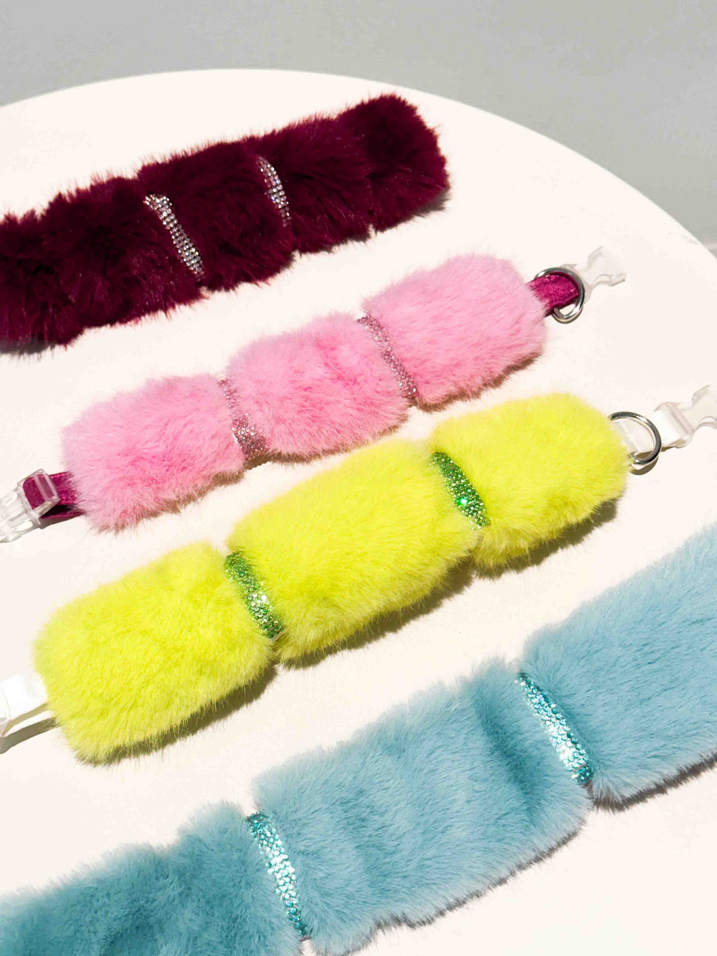A luxurious dog collar featuring sections of burgundy, yellow, pink, and light blue fur with sparkling rhinestone accents, showcasing a colorful and elegant accessory for pets.